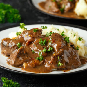beef chuck over mashed potatoes with savory demi sauce